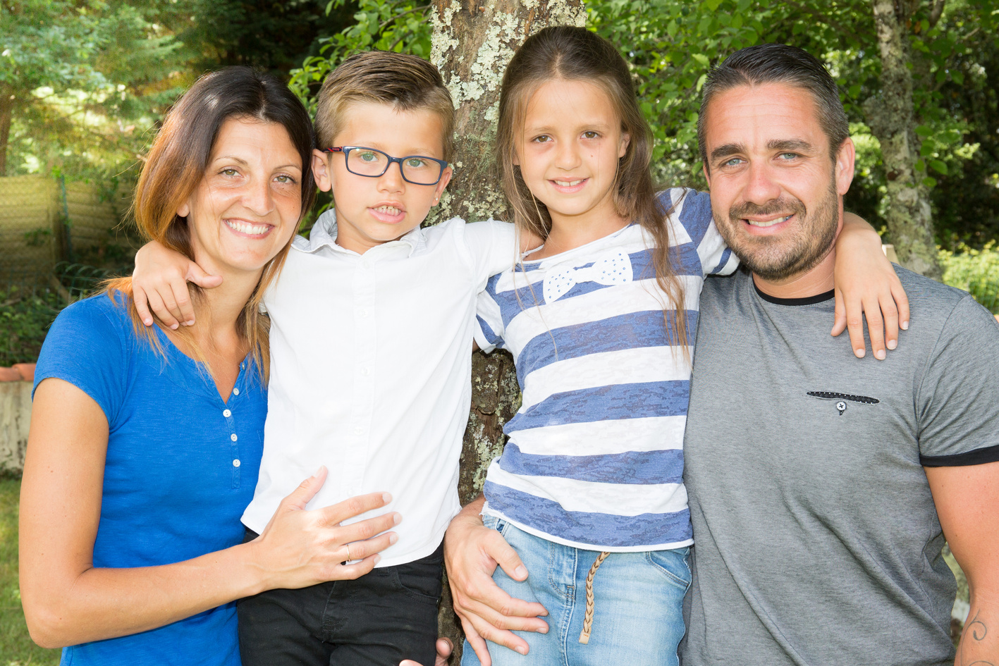 Portrait of happy family of four sitting on bench